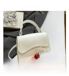 Détail du sac bandoulière en cuir verni blanc avec rabat ondulé et finition brillante