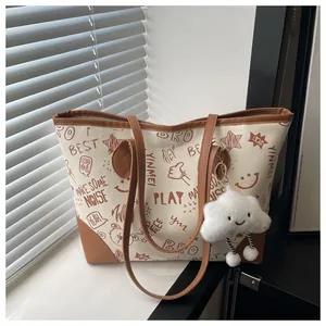 Detail of canvas tote bag with brown leather trim and cute plush cloud keychain charm