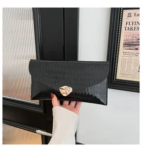 Gros plan d'une pochette enveloppe noire avec texture ondulée et boucle dorée chic