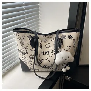 Detail of printed tote bag featuring artistic graffiti and a plush cloud charm accessory