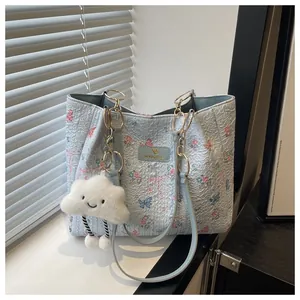 Detail of light blue tote bag with floral butterfly print and cloud charm pendant