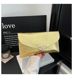 Détail macro d'une pochette enveloppe dorée avec texture ondulée et fermoir métallique