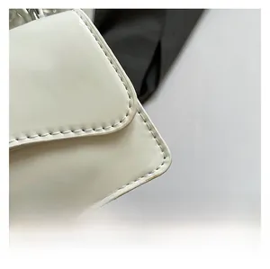 Détail des coutures nettes et de la finition en cuir blanc brillant du sac à bandoulière
