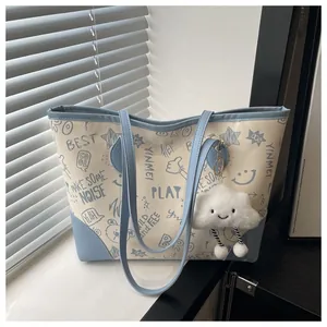 Detail of printed tote bag with blue graffiti patterns and cloud plush charm