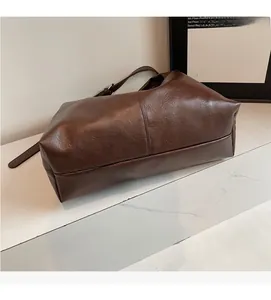 Dettaglio borsa tote in pelle PU marrone con cuciture rinforzate su superficie di marmo