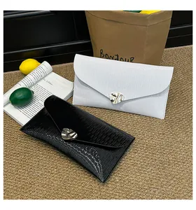Détail d'une pochette enveloppe texturée effet vagues avec boucle en métal doré
