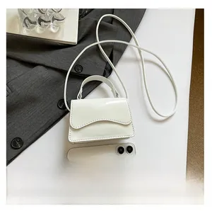 Détail du mini sac blanc en cuir verni avec un smartphone pour comparer la taille