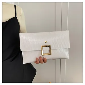 Détail de la pochette enveloppe blanche plissée avec une boucle carrée en métal doré poli