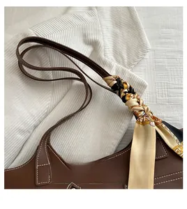 Detail of silk scarf wrapped on handle and white stitching on brown bucket bag