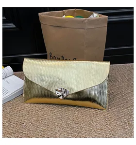 Détail de la pochette enveloppe dorée avec texture ondulée et boucle en métal argenté