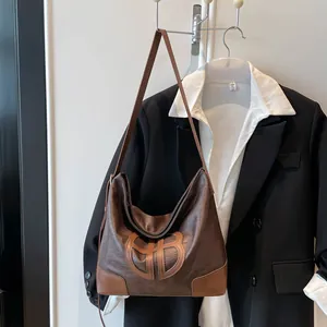 Détail du grand sac hobo marron avec logo gravé et coins de base renforcés en cuir