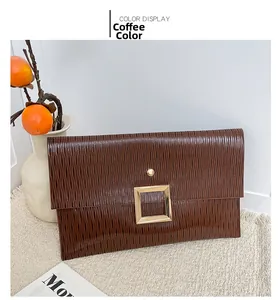 Détail d'une pochette de soirée marron café avec texture verticale et boucle dorée