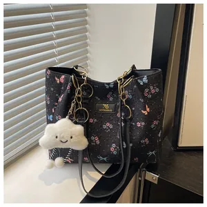 Detail of floral butterfly tote with gold chain and plush cloud charm accessory