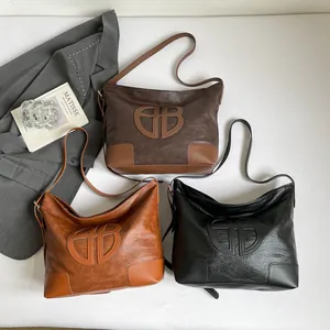 Vue à plat de sacs cabas montrant la texture du cuir et le logo avec accessoires
