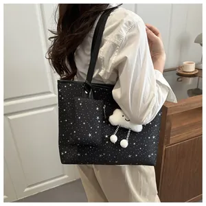 Close-up of black star pattern tote bag with plush charm and matching small pouch