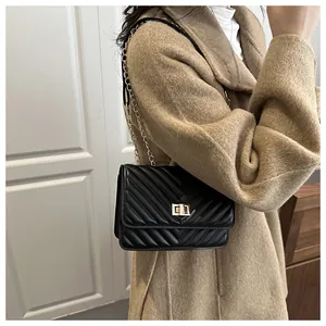 Détail d'un sac à bandoulière noir matelassé avec fermoir doré porté par un mannequin