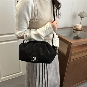 Minimalist black honeycomb textured cloud crossbody bag shown on a model in a cozy setting
