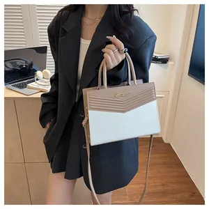 Detail of color-block PU leather handbag with V-shaped quilting and metal logo plate