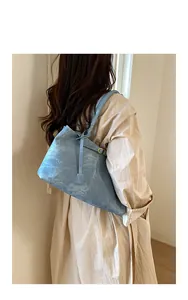 Detail view of light blue suede tote bag with retro metallic ring and long straps