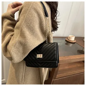 Vue détaillée du sac matelassé noir avec fermoir rotatif doré et bandoulière chaîne