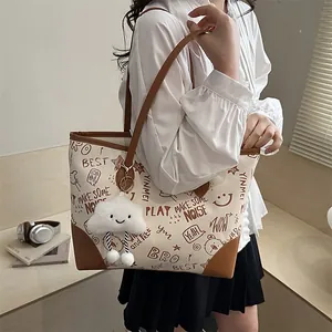 Chic cream tote bag with brown doodle prints and cute plush charm for daily commute