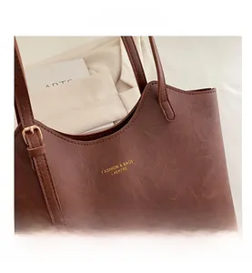 Close-up of brown pebbled leather tote bag with adjustable strap and gold buckle detail