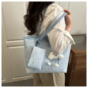 Detail view of a light blue star pattern tote bag with a white cloud plush keychain charm