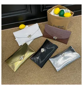 Vue macro de pochettes enveloppes texturées avec boucles dorées en plusieurs couleurs