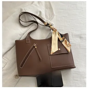 Brown leather bucket tote bag with silk scarf detail and smartphone for size reference