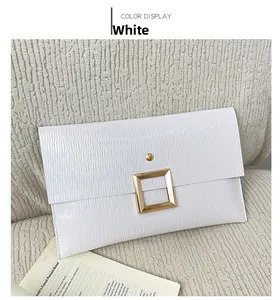 Gros plan sur pochette enveloppe blanche avec texture ondulée et boucle dorée chic