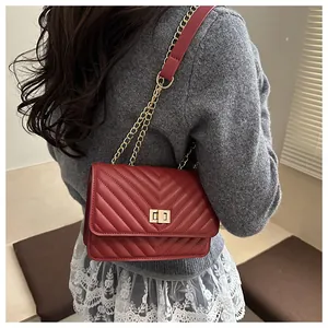 Détail du sac bandoulière rouge matelassé avec chaîne dorée et fermoir pivotant sur mannequin