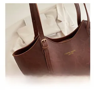 Detail of vintage brown PU leather tote bag with adjustable metal buckle and gold logo