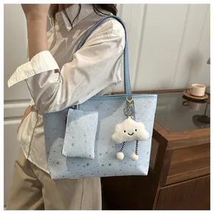 Detail of light blue tote bag with silver star patterns and cloud plush keychain