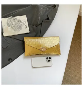 Détail de la pochette enveloppe dorée avec texture plissée et boucle métallique élégante