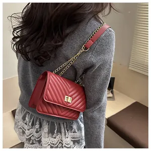 Détail du sac matelassé bordeaux avec fermoir rotatif doré et bandoulière en chaîne