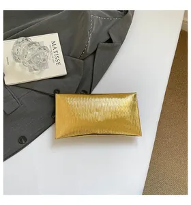 Détail d'une pochette enveloppe dorée de luxe avec texture plissée élégante sur un bureau