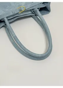 Detail view of the soft light blue tote bag showing the rounded handle and golden D-ring buckle