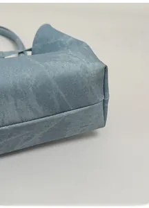 Detailed macro view of the reinforced thick bottom support and twill fabric on a blue tote