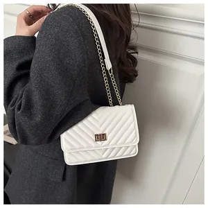 Détail du sac matelassé blanc avec fermoir doré sur une veste de tailleur