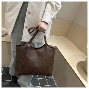 Detail of dark brown tote bag with marble texture and gold lettering on the front