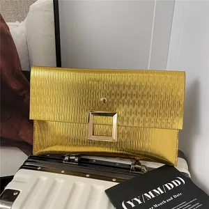 Pochette de soirée enveloppe dorée avec texture ondulée et boucle en métal sur bagage