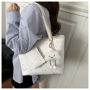 Detail of white tote bag with silver star prints and plush cloud charm on striped shirt