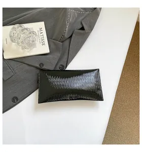 Détail d'une pochette enveloppe noire avec texture ondulée élégante et fini brillant