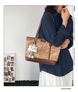 Close-up of contrast color tote bag with plush cloud charm and leather patchwork details