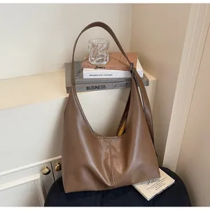 Dettaglio di borsa tote in pelle marrone scuro con ampia tracolla in casa