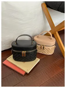 Close-up of beige and black embroidered quilted vanity bags on decorative books