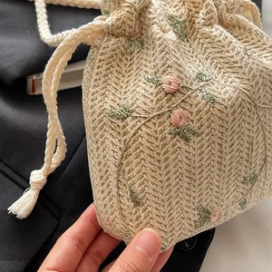 Detail der V-förmigen Stricktextur mit rosa Rosenstickerei auf dem cremefarbenen Beutel