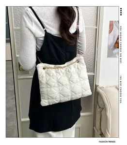 Rear view of a model wearing a white quilted cloud bag with gold chain strap detail