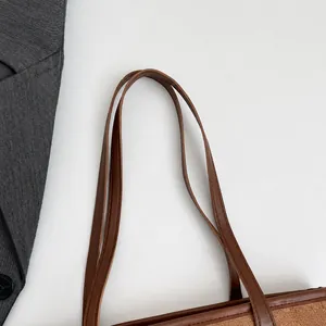 Detail of a brown leather handle with neat stitching on a professional tote bag