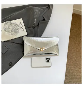 Détail de la pochette enveloppe argentée avec texture plissée et boucle en métal doré